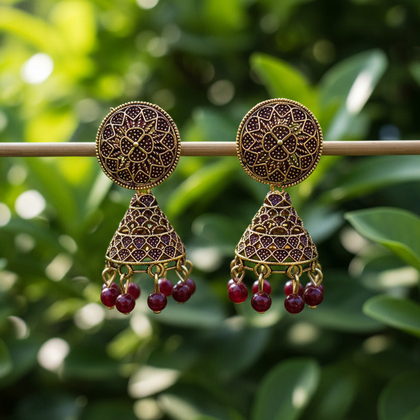 Gold earrings with red gemstones on a gray background
