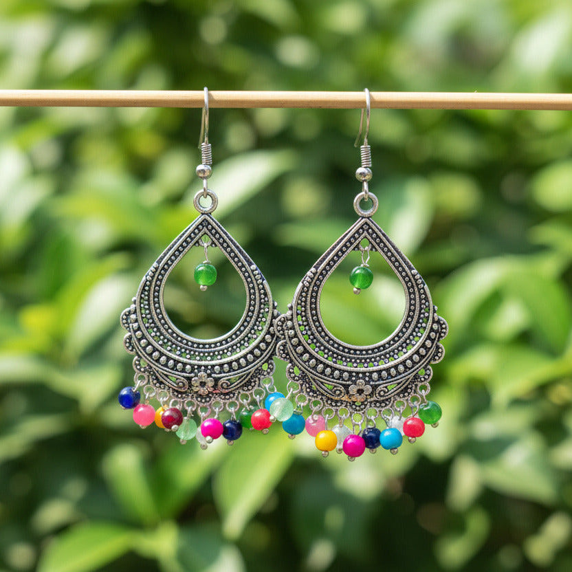 Ornate silver earrings with colorful beads on a dark background