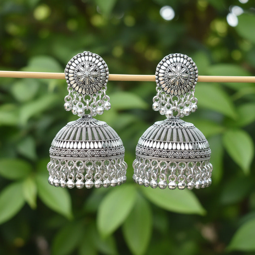 Pair of silver earrings on a stick against a dark background