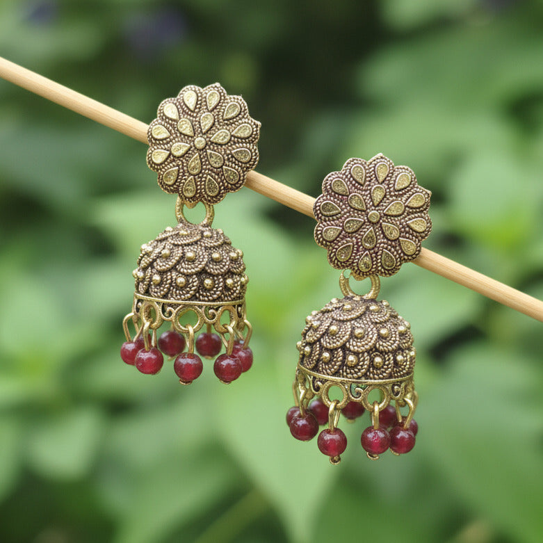 Decorative hairpin with floral designs and red gemstones on a dark background