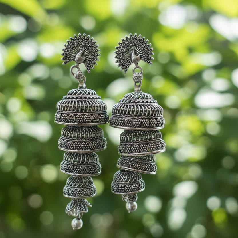 Pair of silver earrings held in front of a blurred background