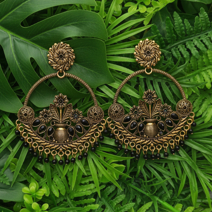 Pair of gold and black earrings on a gray background