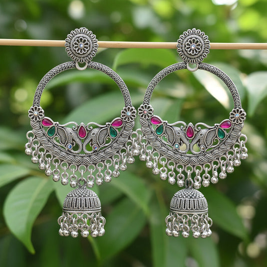 Pair of ornate silver earrings with gemstones on a black background