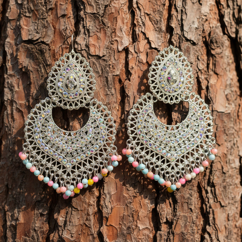 Pair of ornate earrings with rhinestones on a light gray background