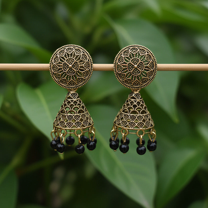 Pair of gold earrings with black beads on a gray background