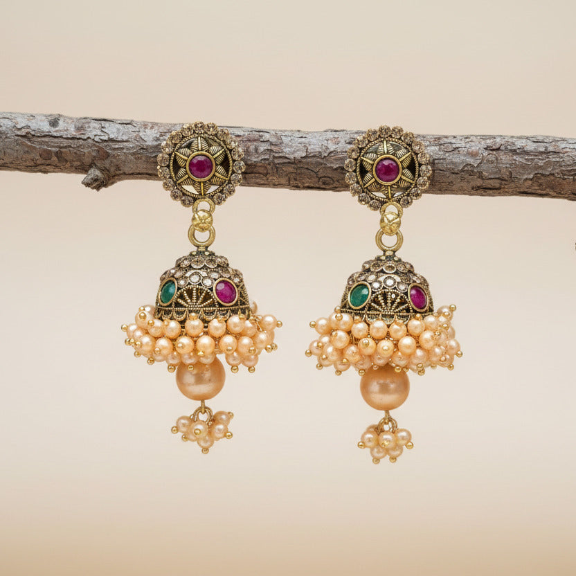 Pair of gold earrings with pearls and gemstones on a blurred background