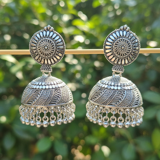 Pair of silver earrings on a stick against a dark background
