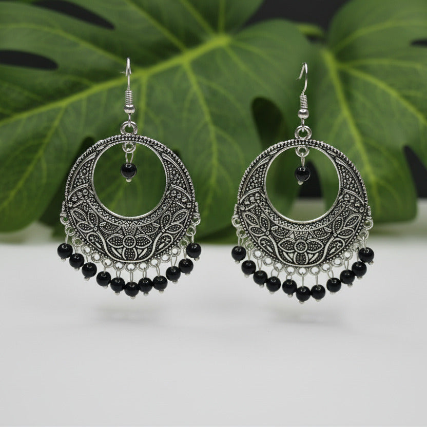 Pair of silver earrings with black beads on a light gray background