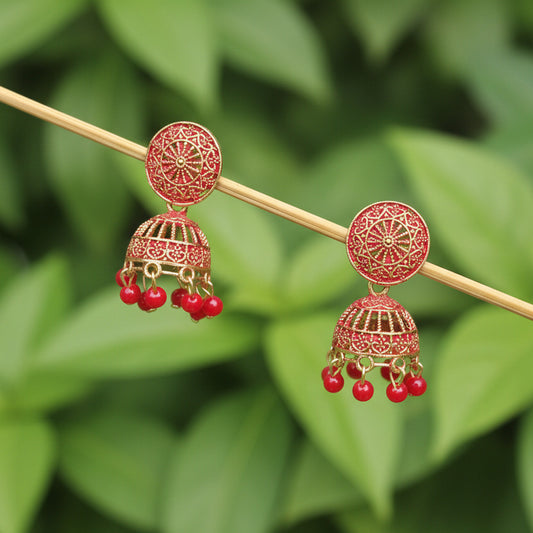 Pair of decorative earrings with red berries on a gray textured background