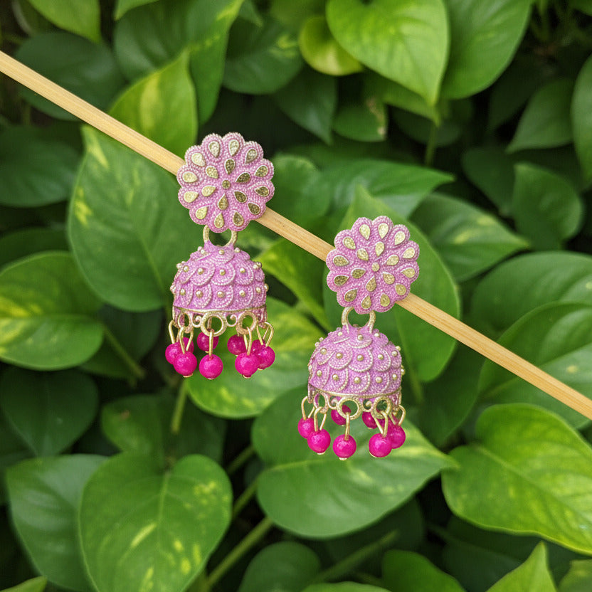 Pair of pink and gold earrings on a gray background