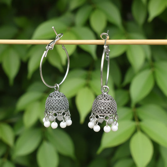 Silver earrings with intricate designs on a gray background