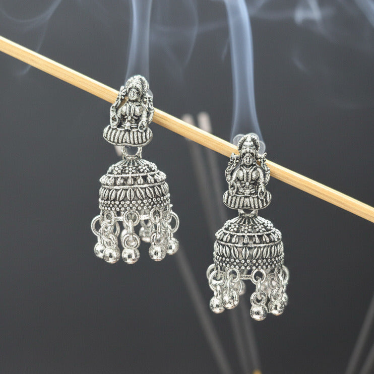 Pair of silver earrings on a dark fabric background