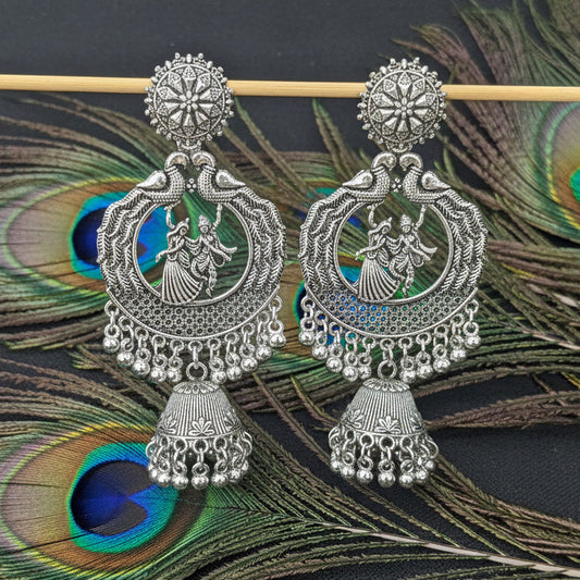 Pair of silver earrings on a dark fabric background
