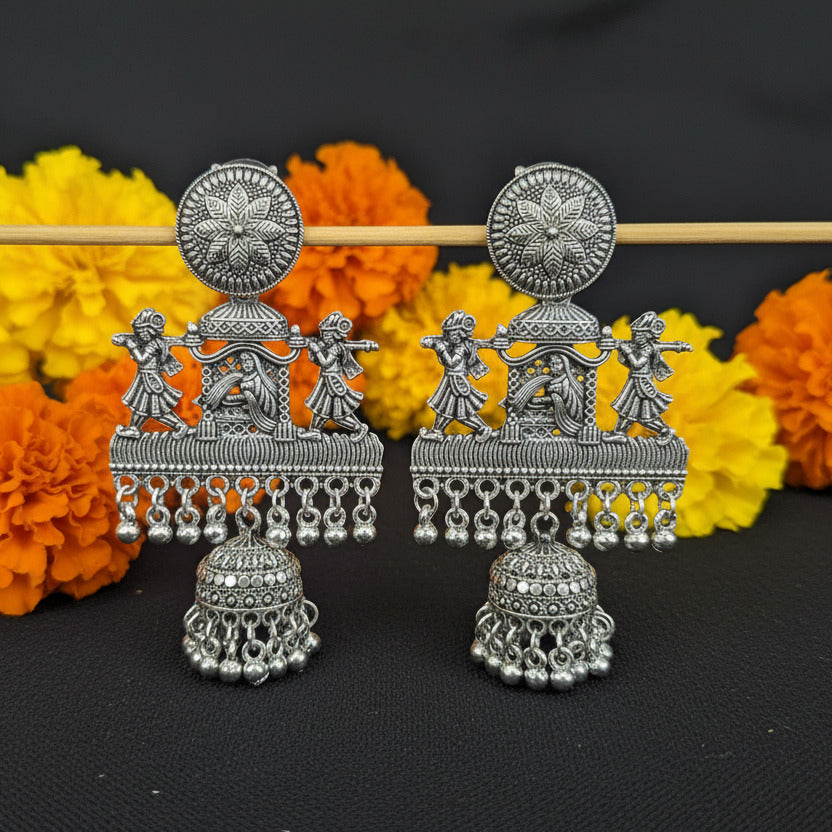 Decorative silver earrings on a black fabric background