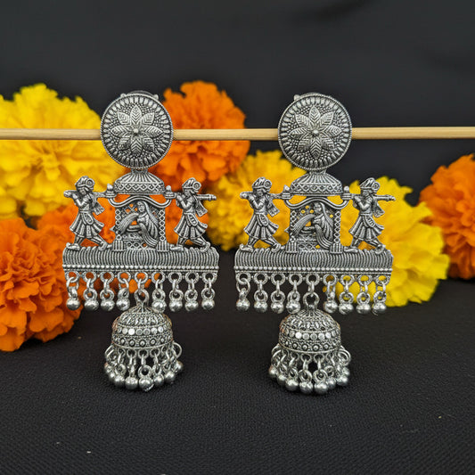 Decorative silver earrings on a black fabric background