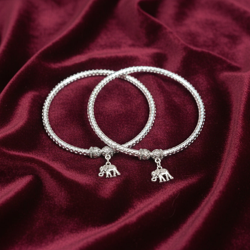 Two silver bracelets with charms on a dark surface