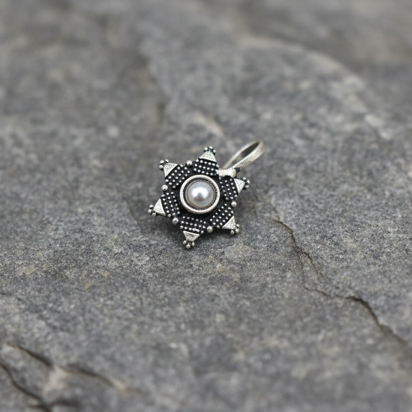 Silver compass-shaped pendant on a white background