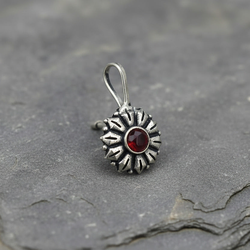 Silver pendant with a purple gemstone on a white card