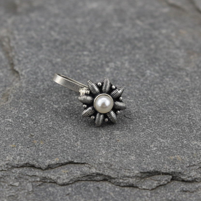 Two silver flower-shaped pendants with gemstones on a light gray background
