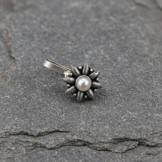 Two silver flower-shaped pendants with gemstones on a light gray background
