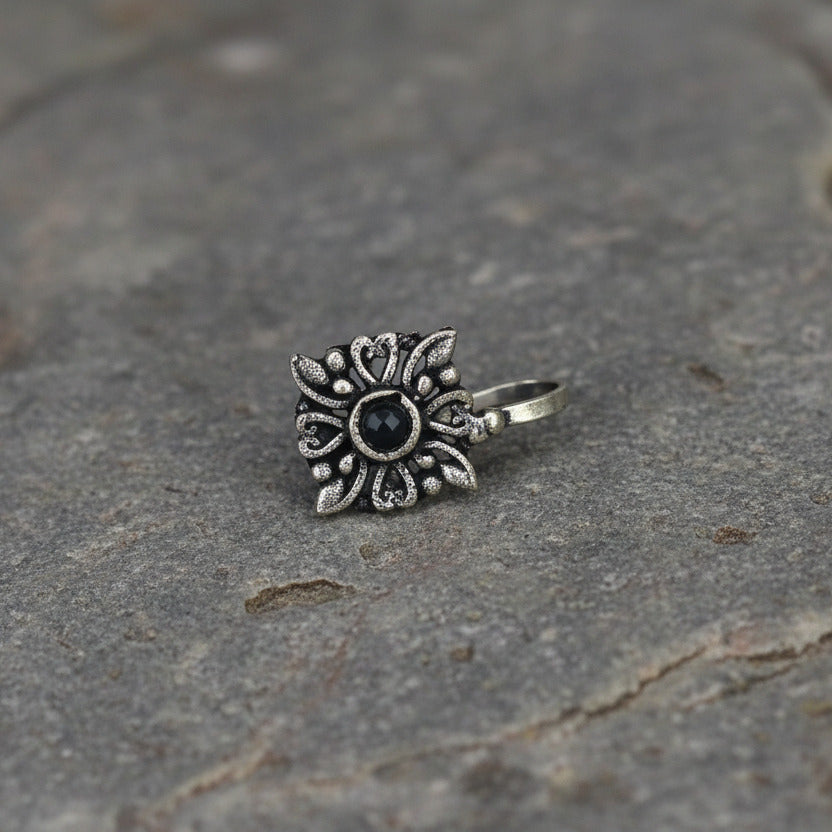 Silver sun-shaped pendant with a black center on a white background