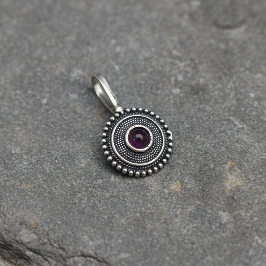 Round metallic object with decorative patterns on a light gray background