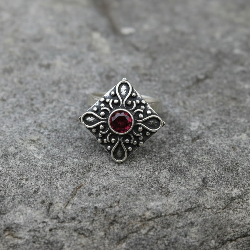 Silver pendant with a purple gemstone on a white background