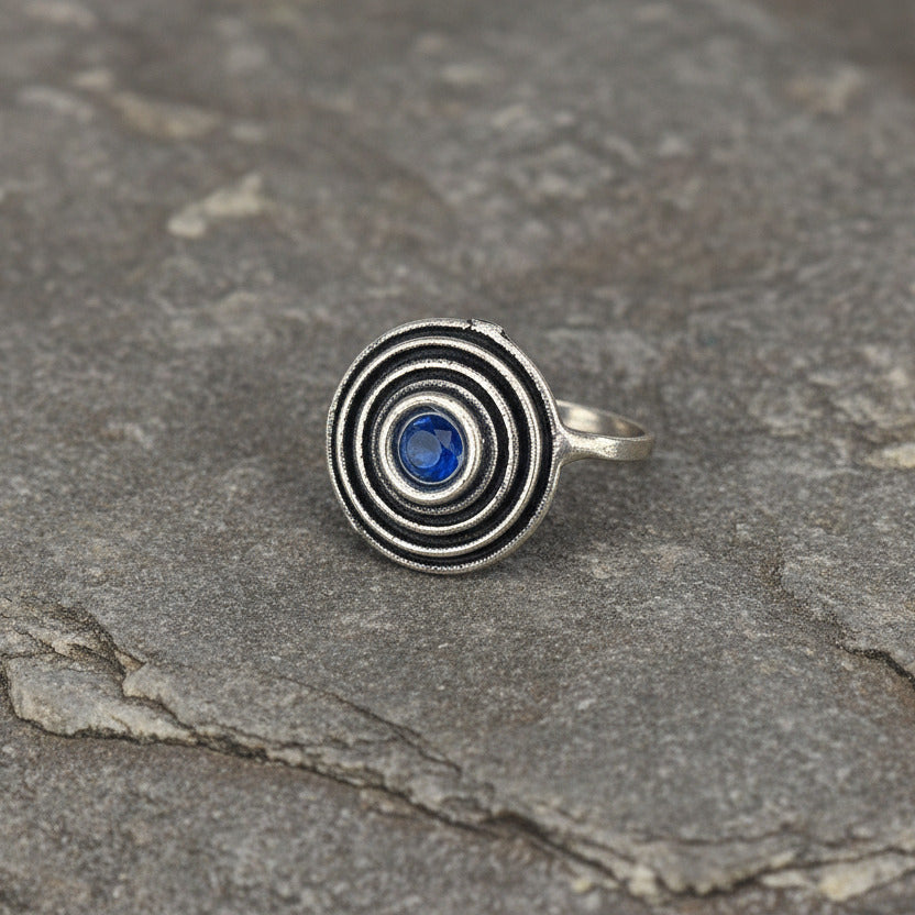 Two silver pendants with blue stones on a white background