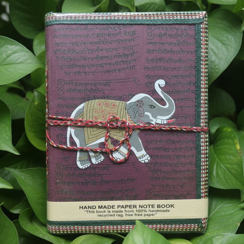 Handmade notebook with elephant design tied with a string on a patterned fabric background