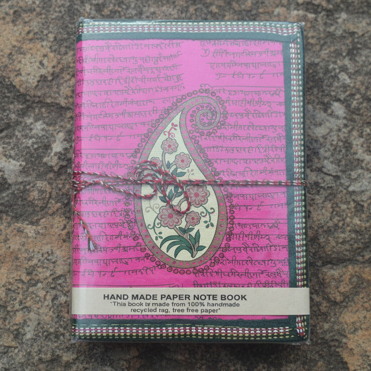 Handmade paper notebook with pink cover and paisley design on a textured surface