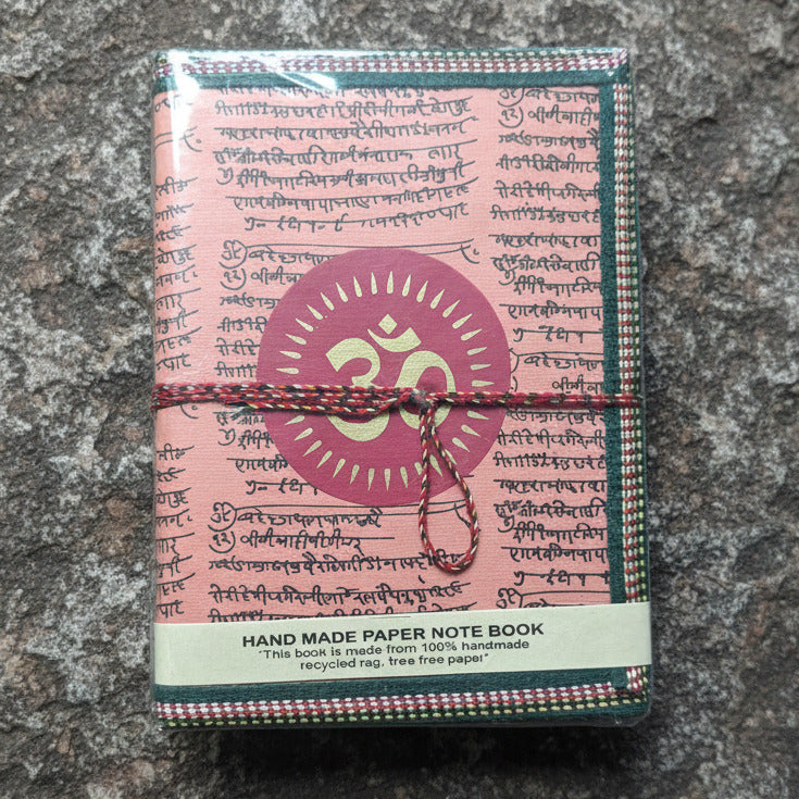 Handmade paper notebook with decorative cover and text on a patterned fabric background