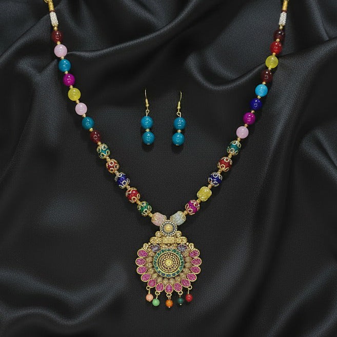 Colorful beaded necklace and earrings on a dark surface with a patterned fabric background.