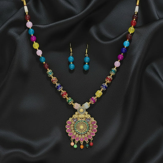 Colorful beaded necklace and earrings on a dark surface with a patterned fabric background.
