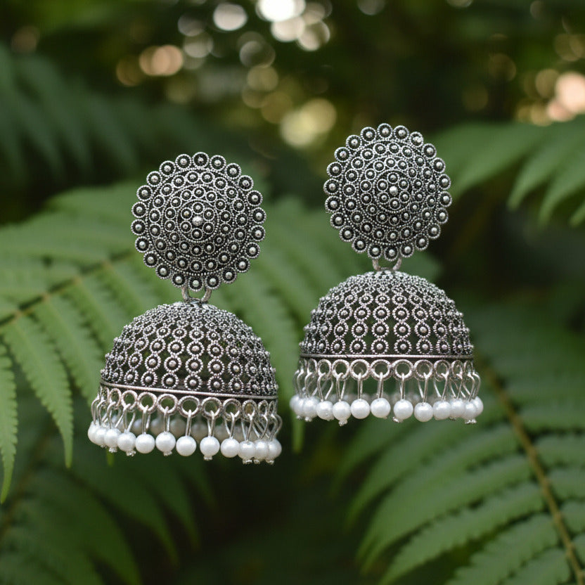 Silver earrings on a Matali branded card held by a person.